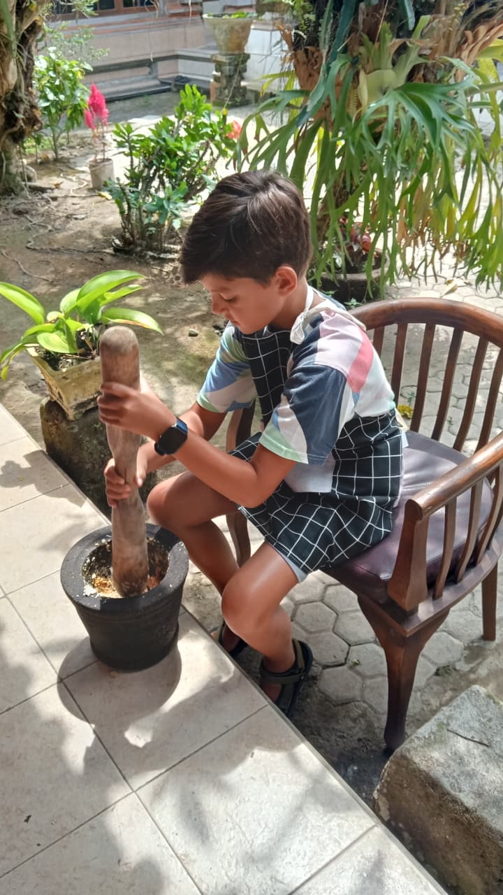 Kid pounding spices in cooking class